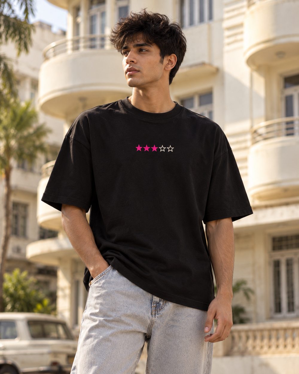 Neo Bombay tee, three-star chest print, standing below art deco balconies